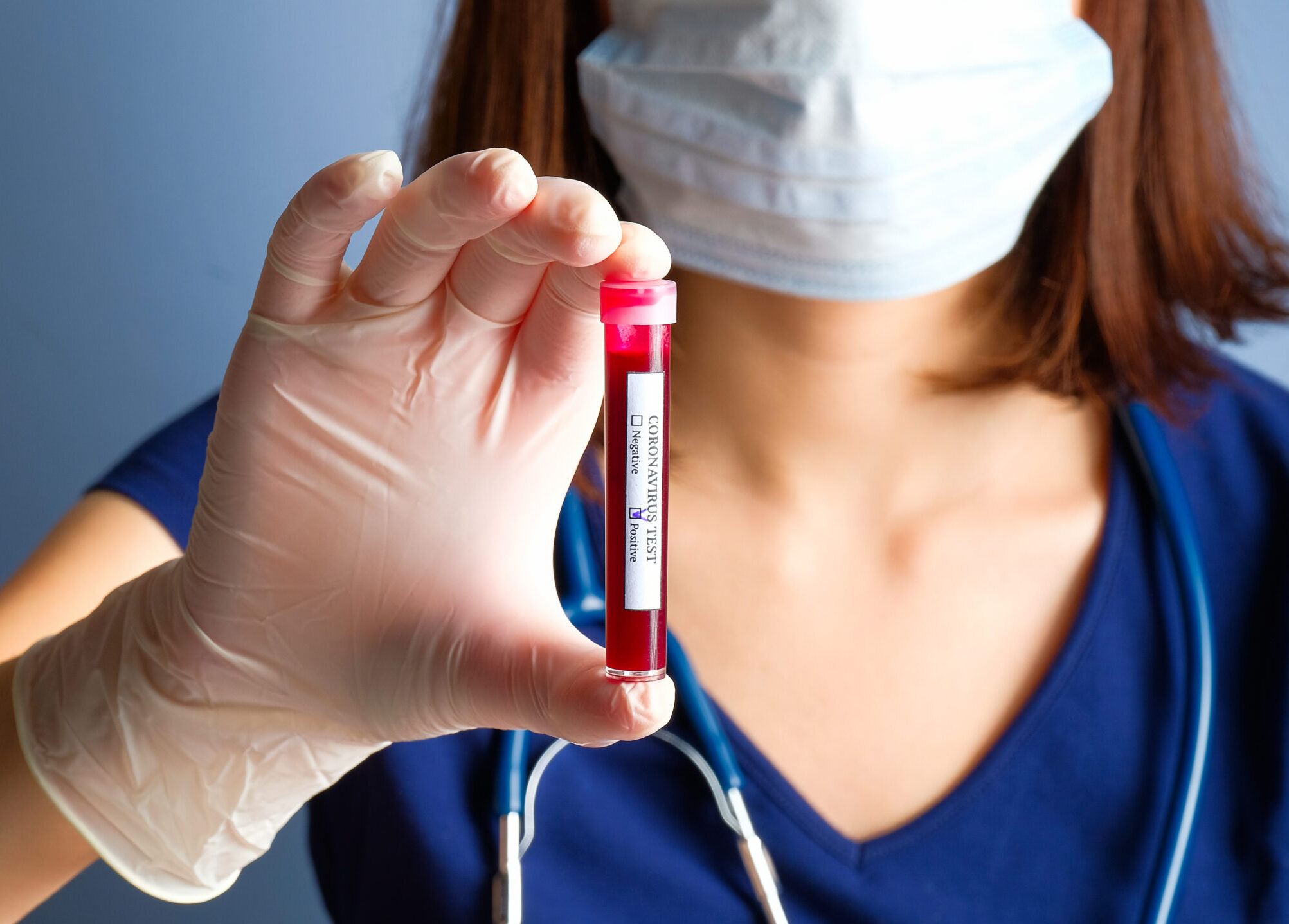 Infirmière, tenant un tube de test avec un échantillon de sang positif pour un test de dépistage du coronavirus.